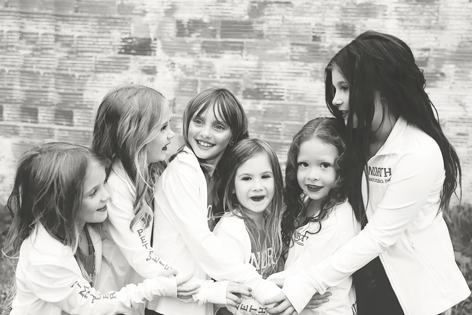 Black and white photo of young North Dance Studio dancers hugging in a group