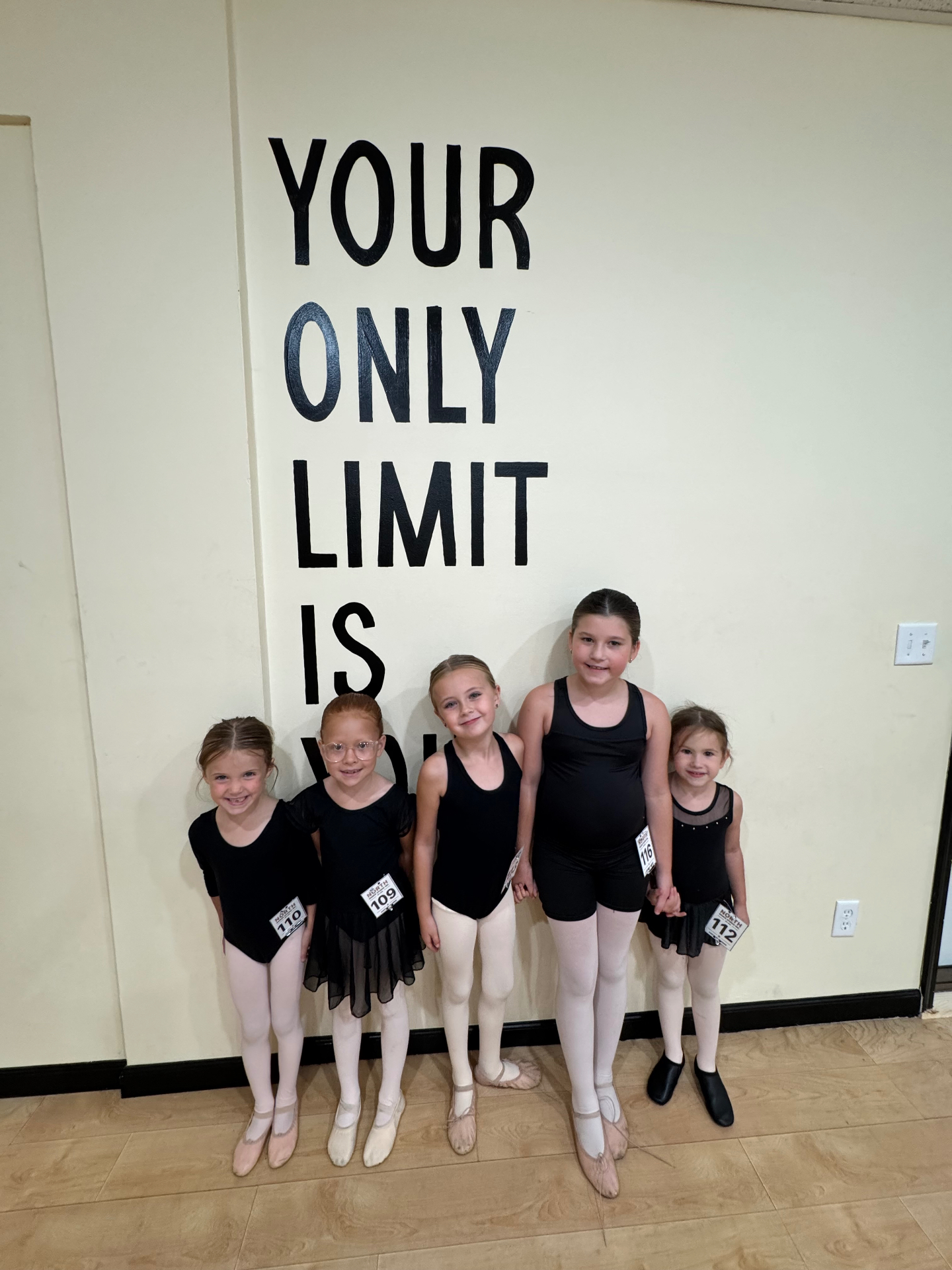 Young ballet dancers lined up under the Your Only Limit Is You wall mural