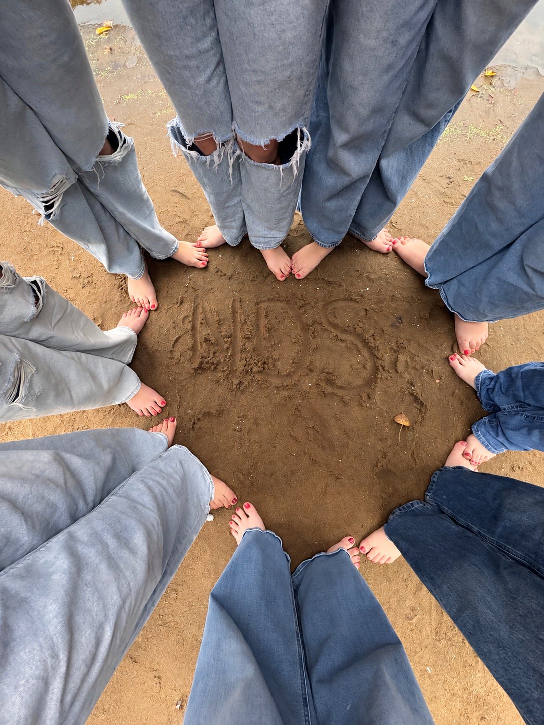 North Dance Studio dancers in a circle around NDS written in the sand