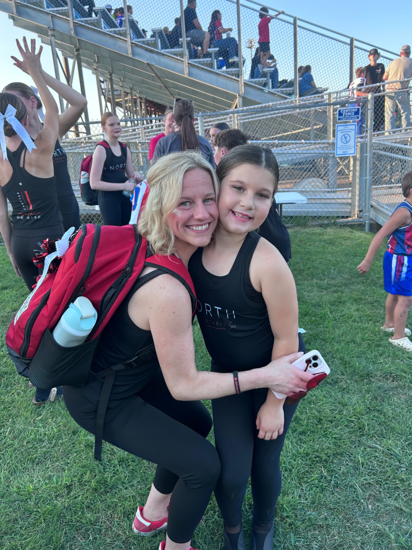 Miss Kristy hugging a young North Dance Studio dancer at the football field