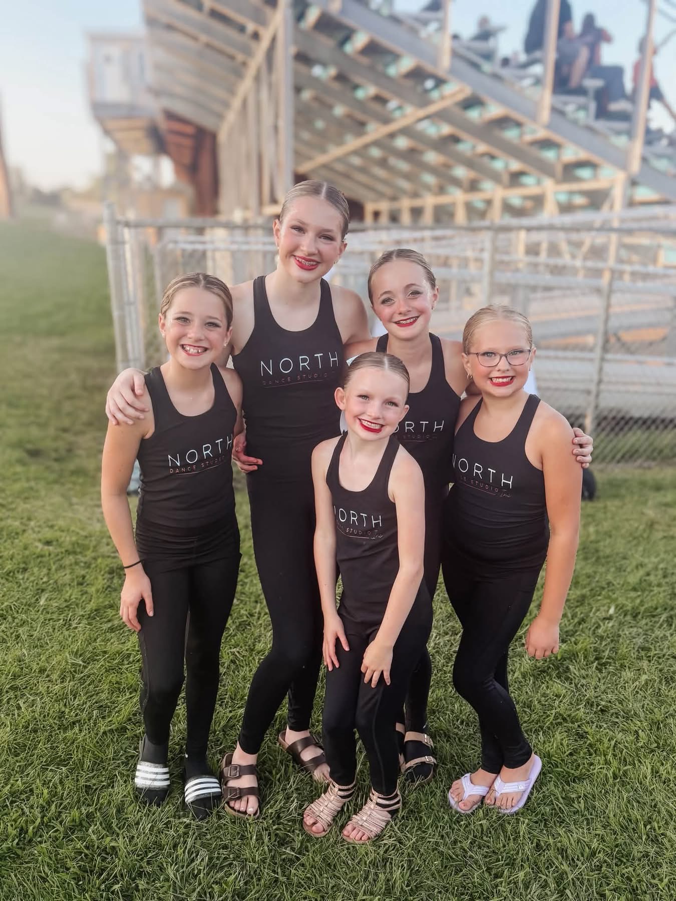 Five North Dance Studio dancers smiling together at the football field