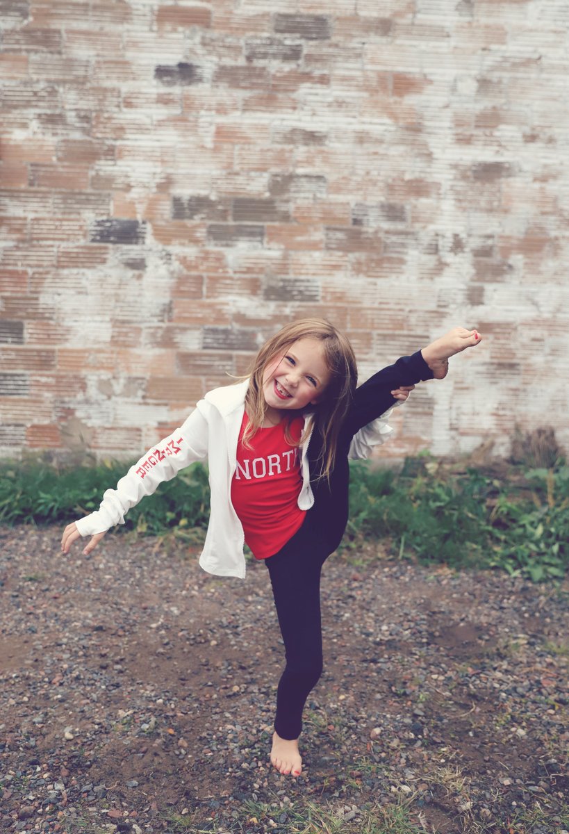 A young North Dance Studio dancer kicking high in front of a brick wall
