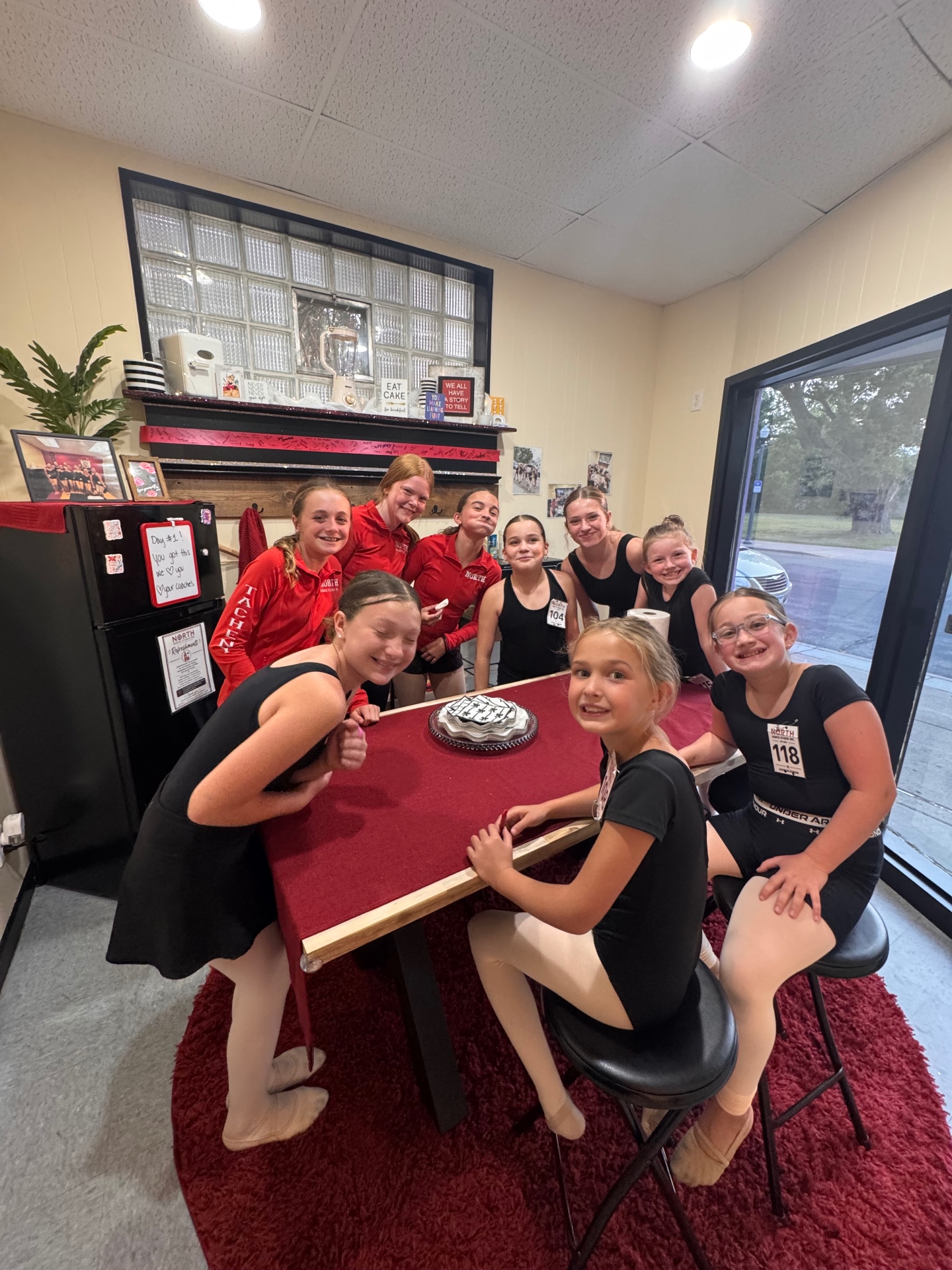 Dancers gathered around a cake in the North Dance Studio lobby