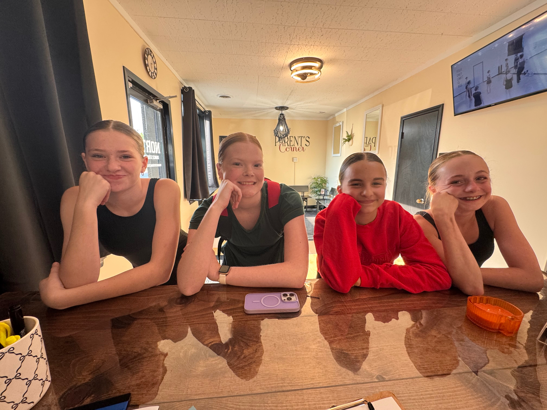 Four North Dance Studio dancers smiling at the lobby table in the Parent's Corner