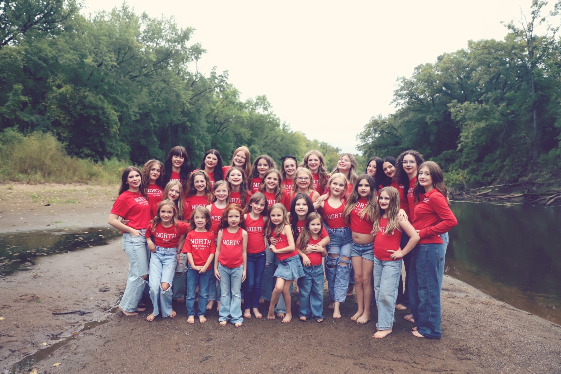The full North Dance Studio team in red NORTH shirts by the river